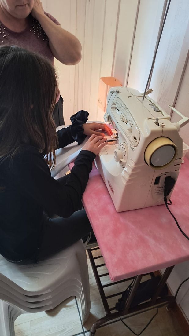 Adolescente costurando em uma máquina de costura durante a oficina