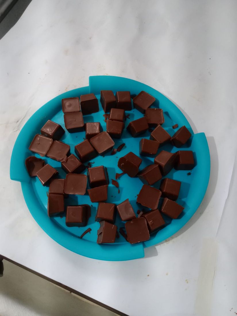 Bombons de chocolate prontos em uma bandeja azul, produzidos na aula de culinária