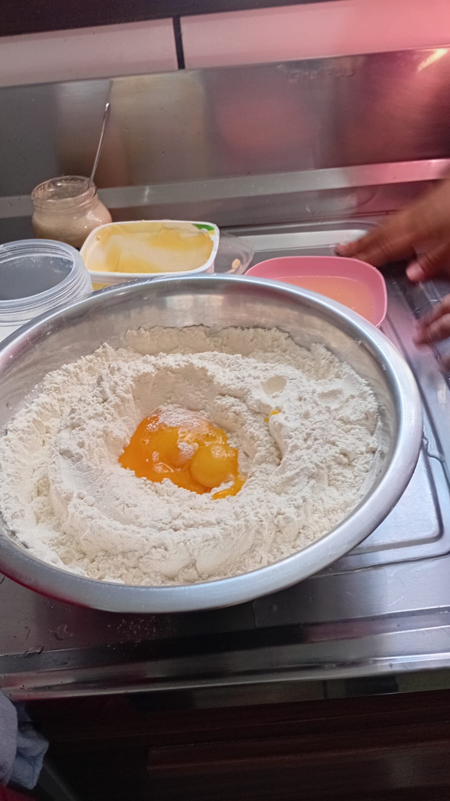 Bacia de alumínio com farinha de trigo e ovos no centro, preparada para a receita de pão